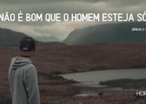 Um homem sozinho no campo, com a vista de um lago.