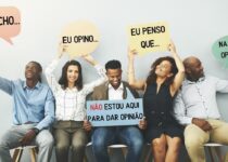 Jovens sentados com cartazes em forma de "balão de conversa" e frases como "Eu acho" e "Eu creio". No centro a frase "Não estou aqui para dar opinião"