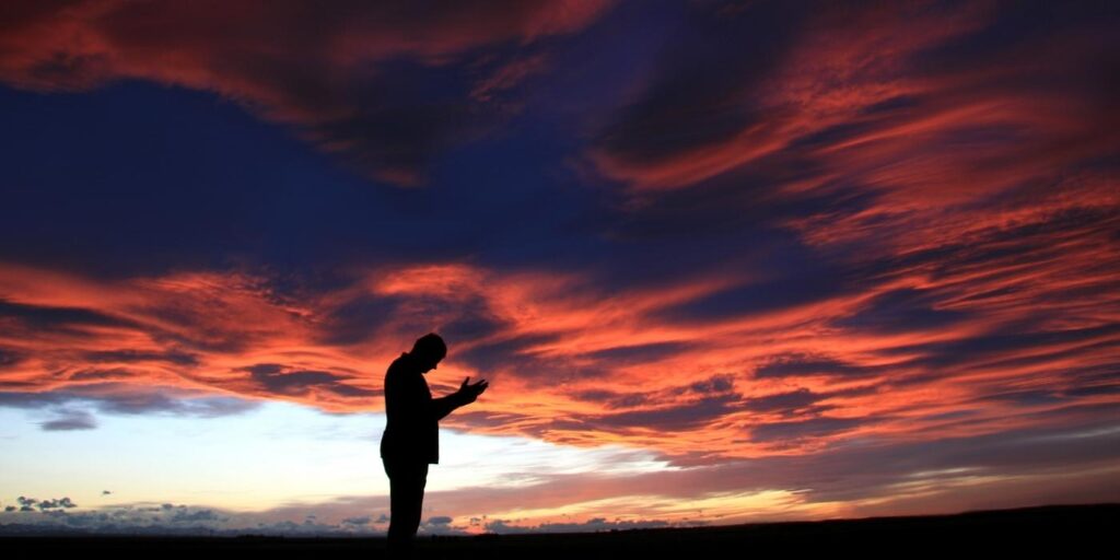 Homem ora baixo céu vermelho